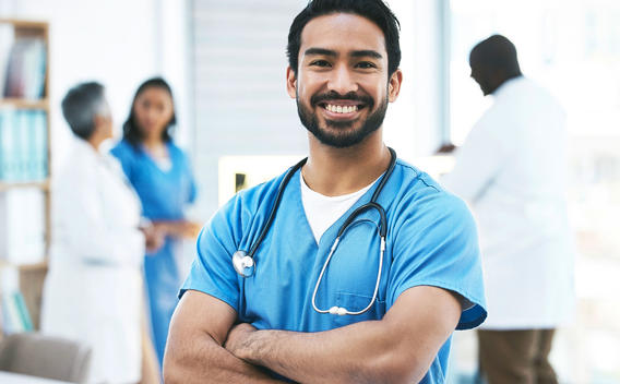 Male nurse smiling with medical staff in the background