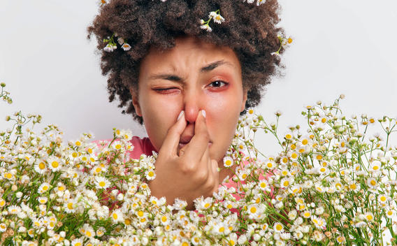 Woman plugging nose and showing signs of pollen allergies