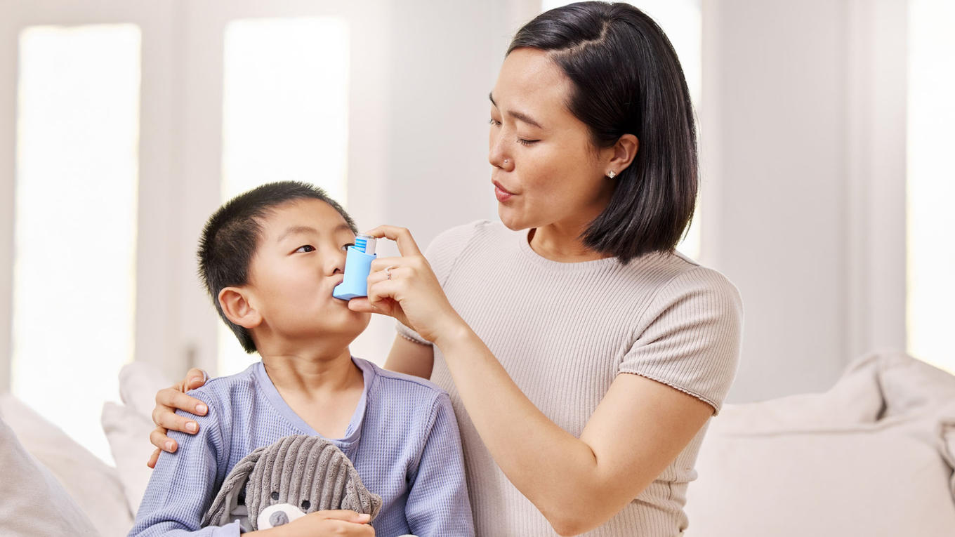 Mother applying asthma inhaler to her child